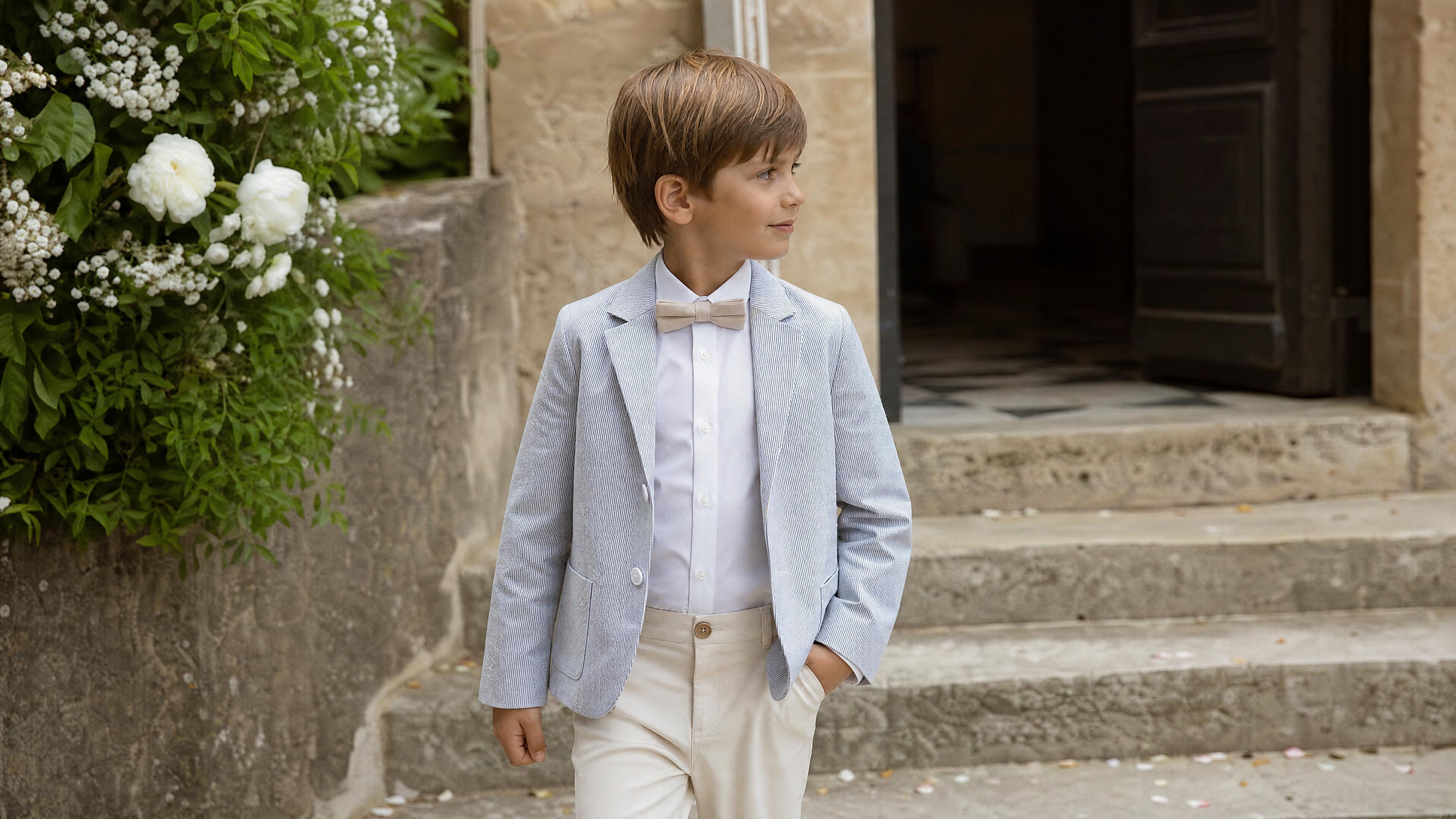 Garçon en tenue de cérémonie avec accessoires adaptés pour un mariage. Bild