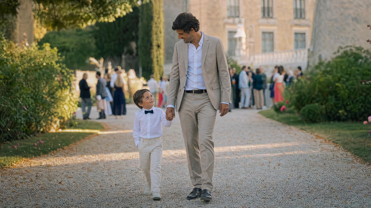 Enfant habillé pour un mariage marchant avec un adulte, tenue élégante et confortable. Bild